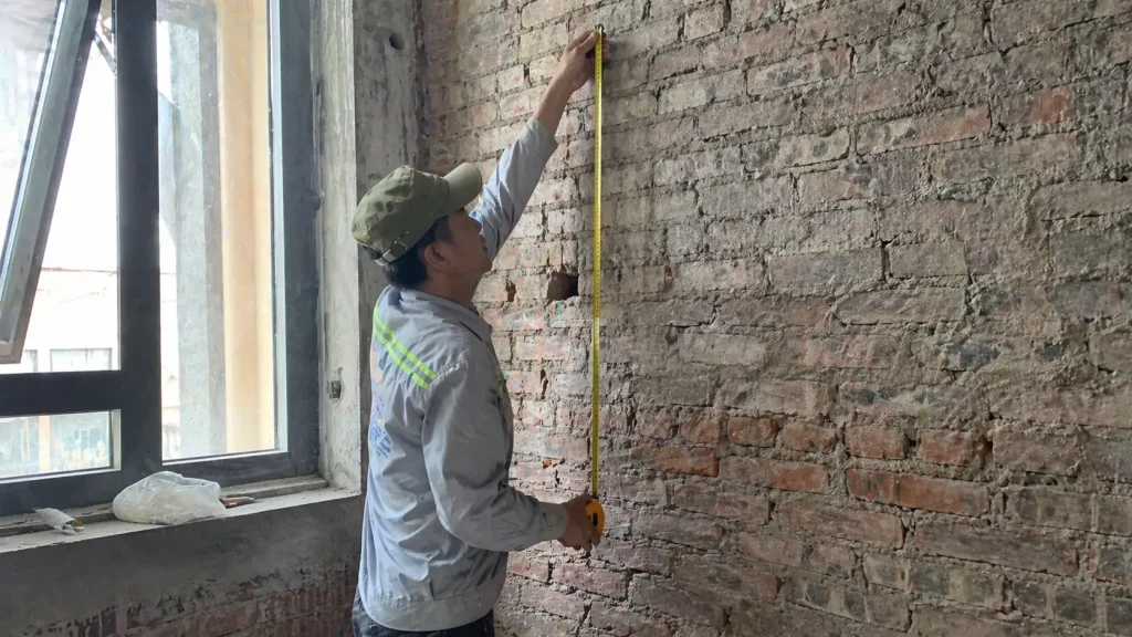 Thợ thi công đang đo đạc để áp dụng cách tính tấm nhựa vân đá thực tế