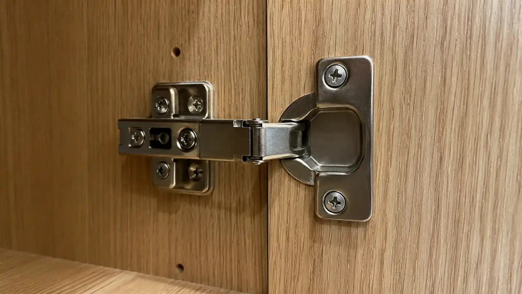 Cận cảnh bản lề giảm chấn inox bắt vít chắc chắn vào vách tủ nhựa