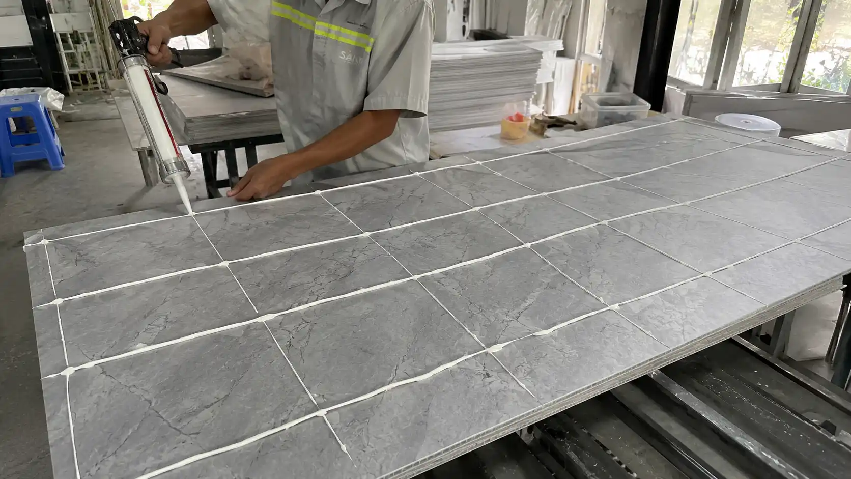 Quá trình thợ bôi keo dán chuyên dụng lên mặt sau tấm nhựa vân đá
