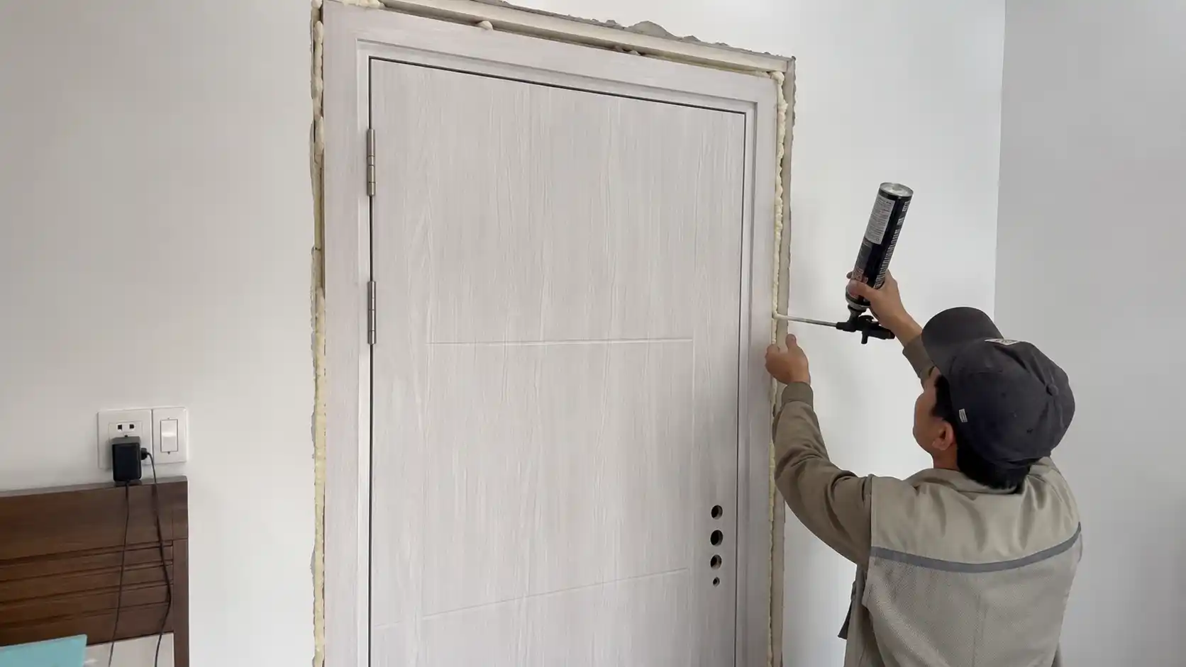 Công đoạn thợ bắn keo bọt cố định khung bao cửa nhựa composite phòng ngủ