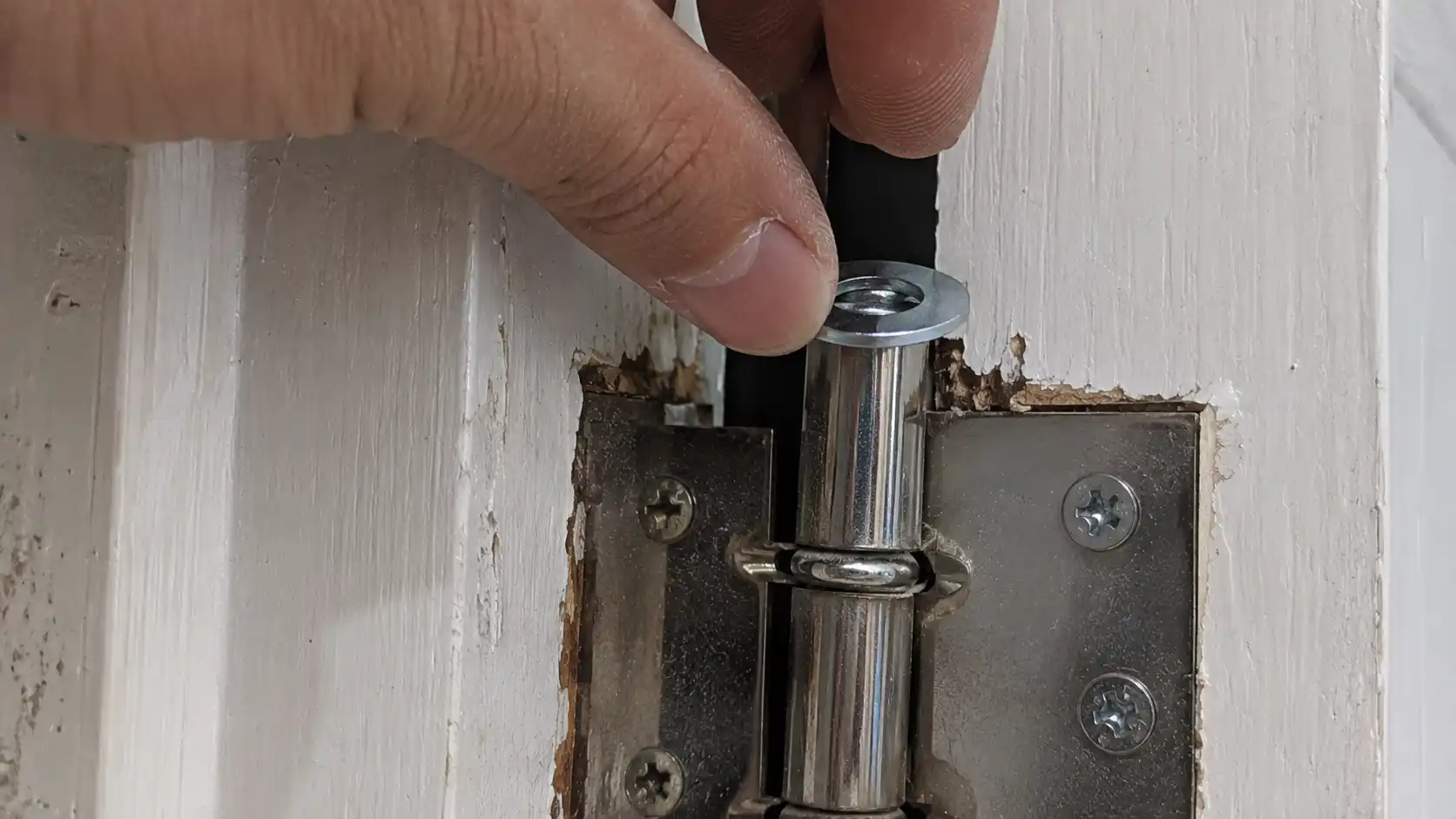 Thợ mộc chêm vòng đệm (long đền) vào trục bản lề để đôn cửa