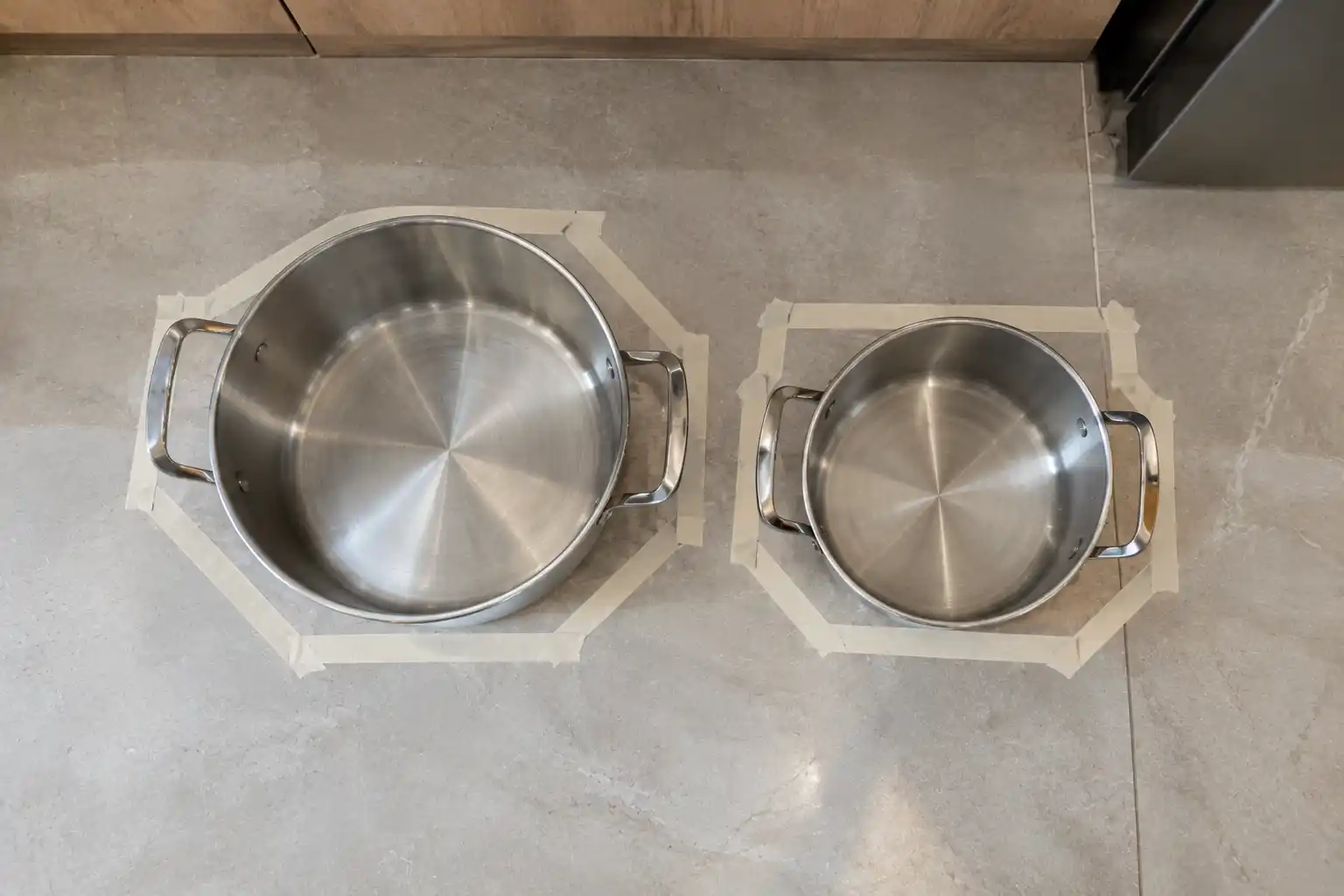 Hai nồi xếp cạnh nhau đánh dấu bằng băng keo để tính kích thước giá để xoong nồi